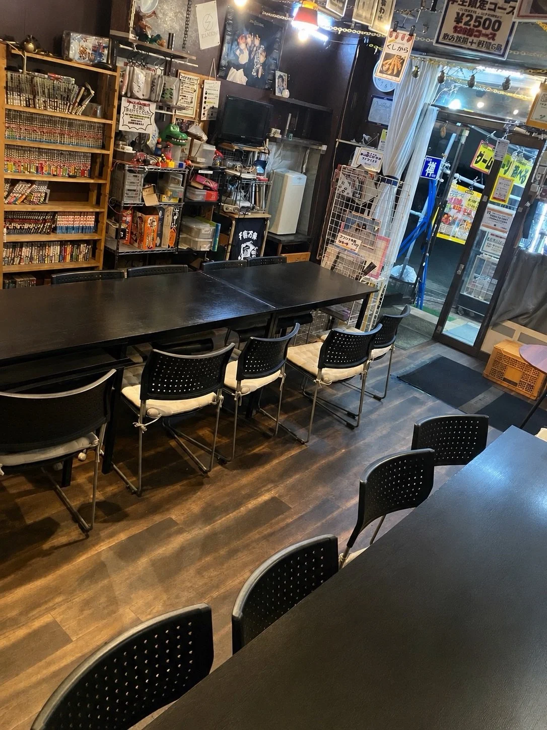 木目の本棚とテーブル席が並ぶ居酒BAR禅の店内